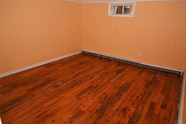 unfurnished room with baseboards, dark wood-style flooring, and a baseboard heating unit