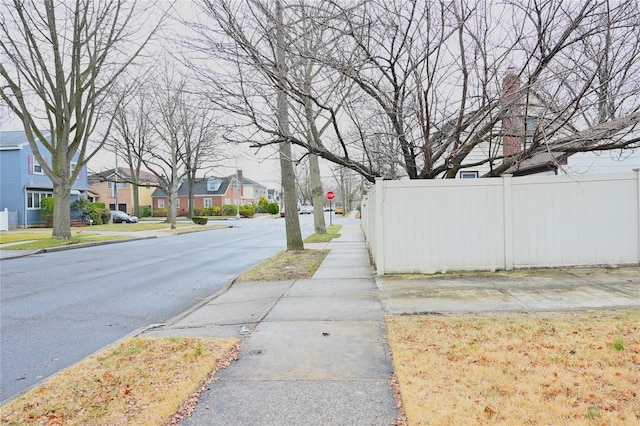 view of street with curbs, traffic signs, sidewalks, and a residential view