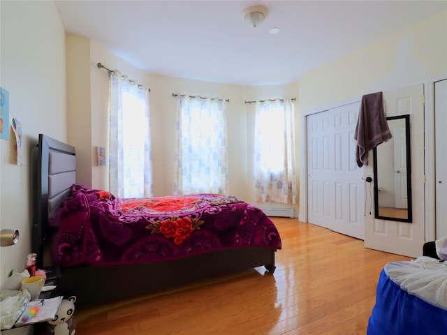 bedroom featuring light wood finished floors and a baseboard heating unit