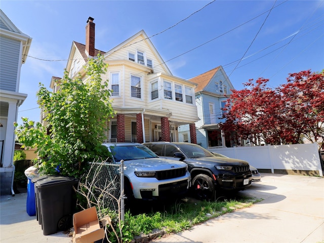 view of front of home with brick siding, fence, and a chimney