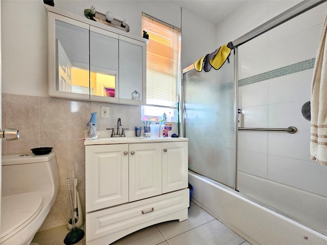 full bath featuring tile walls, tile patterned flooring, vanity, toilet, and shower / bath combination with glass door