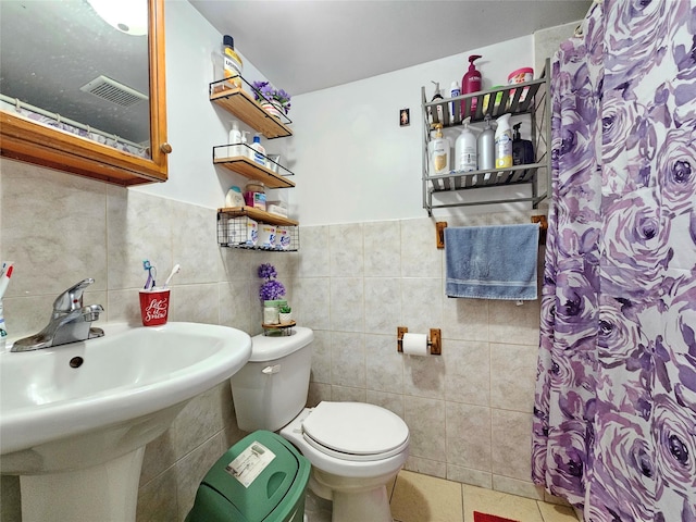 bathroom featuring a sink, tile patterned flooring, toilet, tile walls, and curtained shower