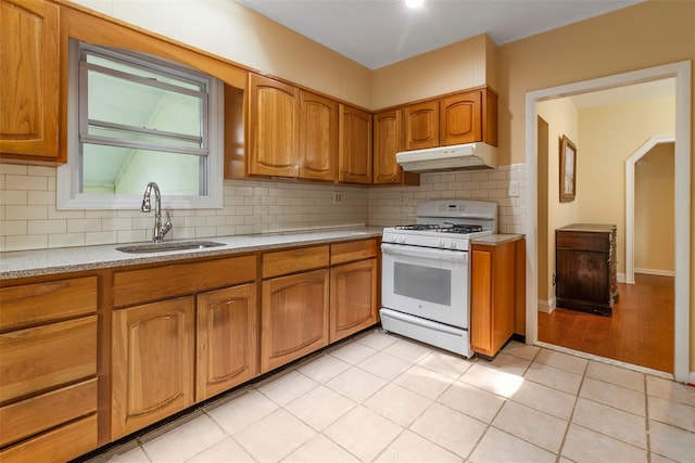 7 Cobblestone Ln, Cortlandt Manor, NY 10567 - kitchen featuring white range with gas stovetop, under cabinet range hood, decorative backsplash, brown cabinets, and light tile patterned flooring