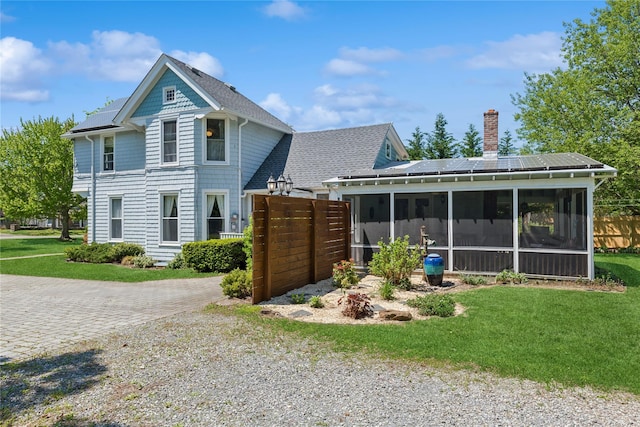 264 Washington Ave, Jamesport, NY 11947 - back of house with a sunroom, a chimney, a shingled roof, and driveway