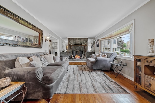 living room with wood finished floors, a fireplace, baseboards, and ornamental molding