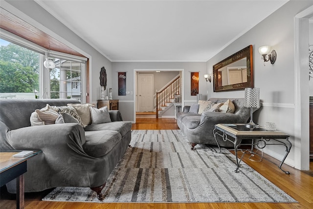 living room featuring stairs, wood finished floors, baseboards, and crown molding