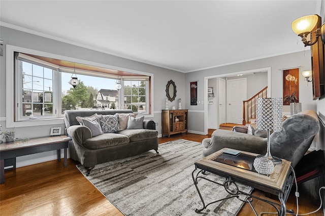 living area with wood finished floors, stairs, crown molding, and baseboards