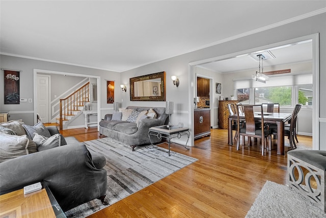 living room with stairs, light wood-type flooring, and crown molding