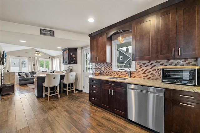 kitchen with stainless steel dishwasher, a sink, a kitchen bar, open floor plan, and ceiling fan
