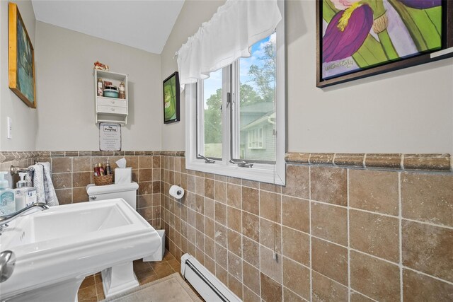 bathroom featuring tile walls, a sink, tile patterned flooring, wainscoting, and lofted ceiling