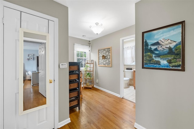 hallway featuring light wood-style flooring and baseboards