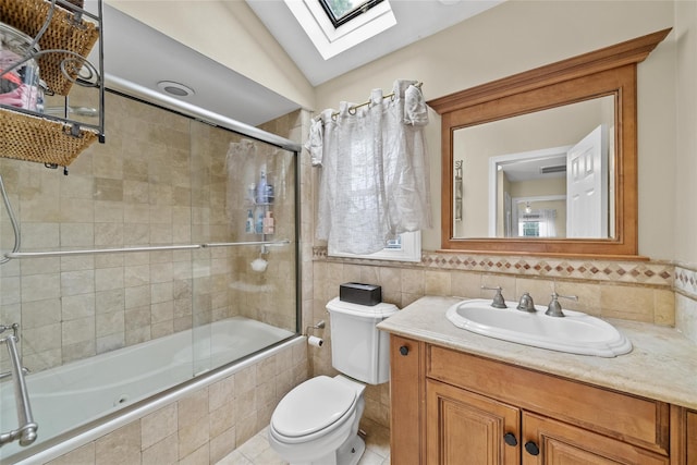 full bathroom with a skylight, tiled shower / bath combo, toilet, tile walls, and vanity