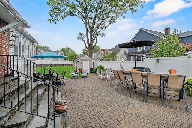 view of patio featuring a shed, a fenced backyard, an outdoor structure, and a residential view