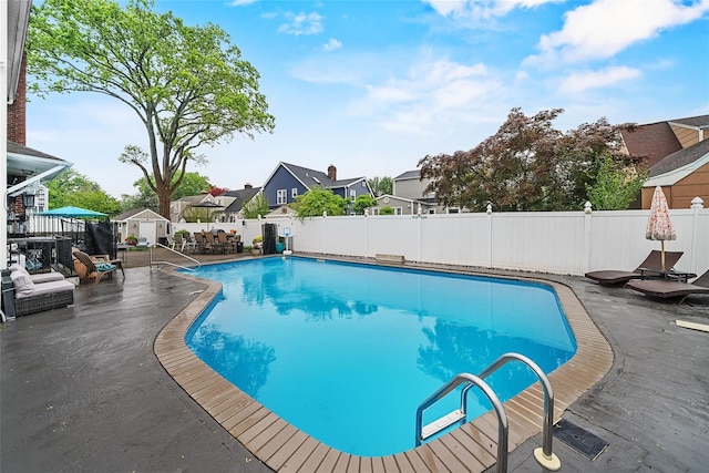 view of pool featuring a fenced backyard, an outbuilding, a shed, a residential view, and a patio