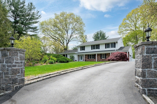 traditional-style house with brick siding, a garage, aphalt driveway, and a front yard