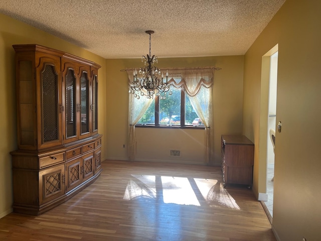 45 Princeton Dr, Tappan, NY 10983 - unfurnished dining area with light wood-style floors, a chandelier, and a textured ceiling
