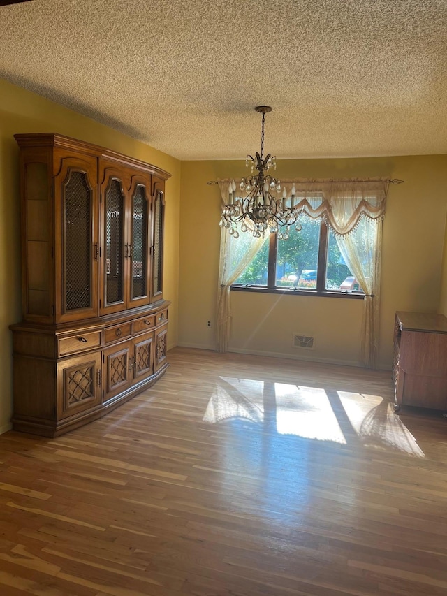 45 Princeton Dr, Tappan, NY 10983 - unfurnished dining area with a textured ceiling, a chandelier, and light wood-type flooring