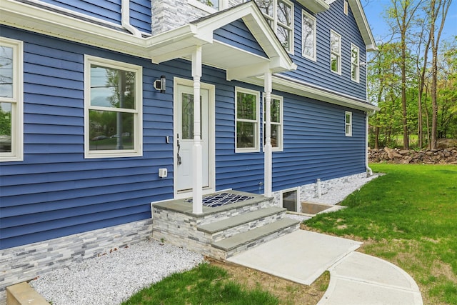 view of exterior entry featuring a lawn