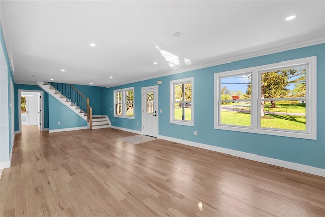 unfurnished living room with crown molding, stairway, and baseboards