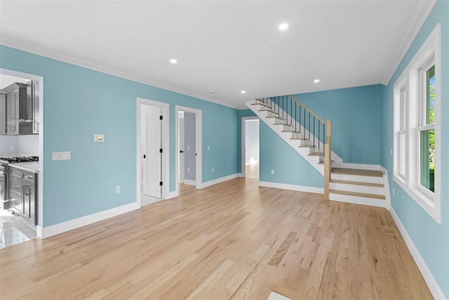 unfurnished living room featuring ornamental molding, stairs, plenty of natural light, and light wood-style floors