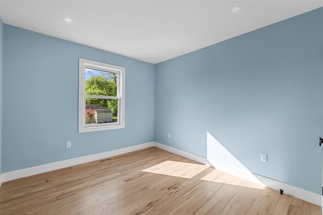 unfurnished room with baseboards, light wood-type flooring, visible vents, and recessed lighting