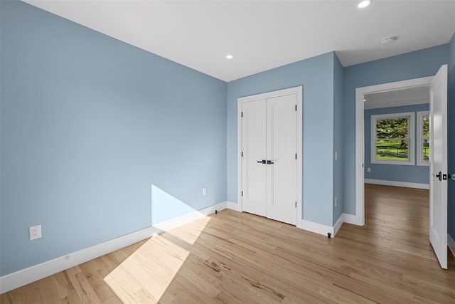 unfurnished bedroom featuring baseboards, recessed lighting, light wood finished floors, and a closet