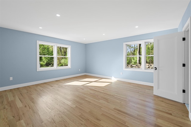 empty room with recessed lighting, a wealth of natural light, baseboards, and light wood-style floors
