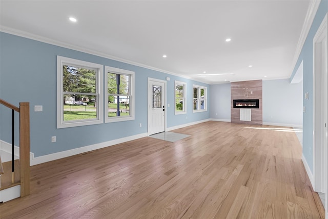 unfurnished living room featuring light wood finished floors, crown molding, stairway, and baseboards