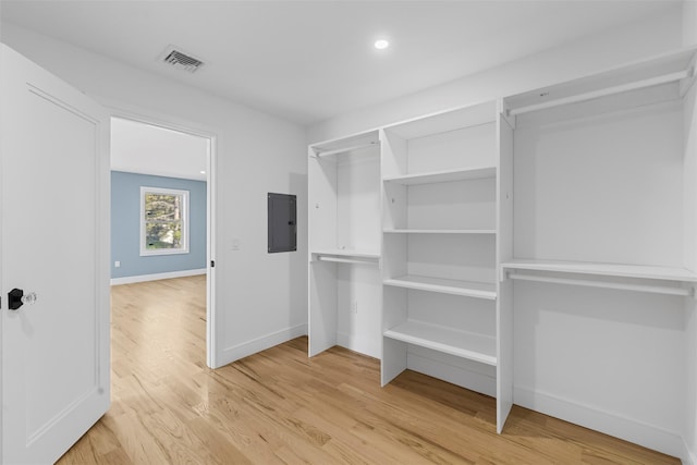 walk in closet with light wood-style floors, visible vents, and electric panel