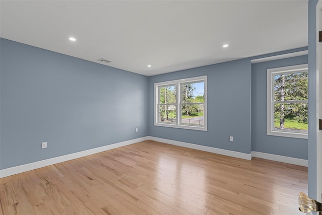 empty room with baseboards, light wood-style floors, visible vents, and plenty of natural light