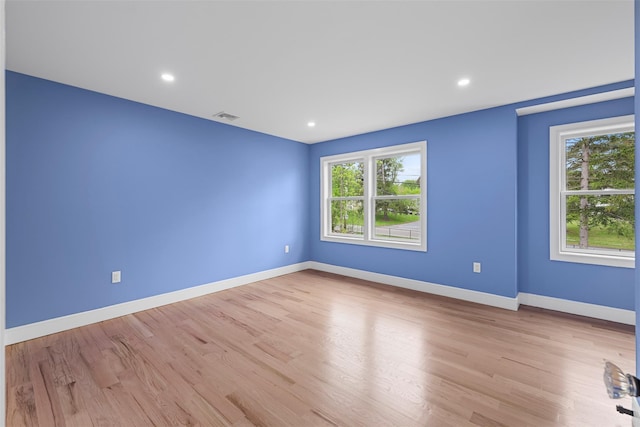 spare room with wood finished floors, plenty of natural light, and visible vents