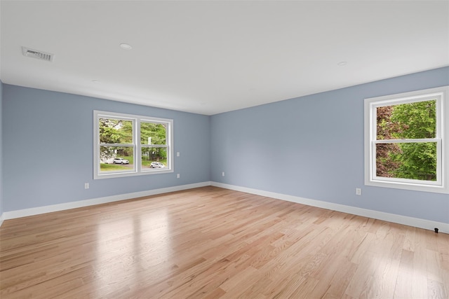 spare room with baseboards, light wood-type flooring, and visible vents