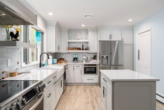6 Circle Dr, Shoreham, NY 11786 - kitchen with appliances with stainless steel finishes, exhaust hood, open shelves, decorative backsplash, and light wood-style floors
