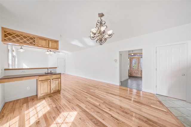unfurnished dining area with baseboards, light wood-style flooring, and a notable chandelier
