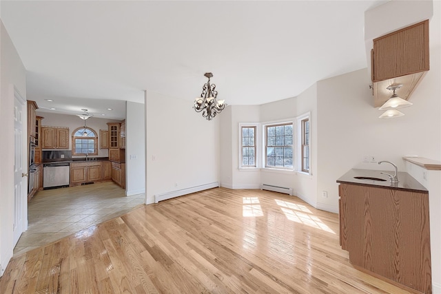 unfurnished dining area featuring an inviting chandelier, a sink, and a baseboard heating unit
