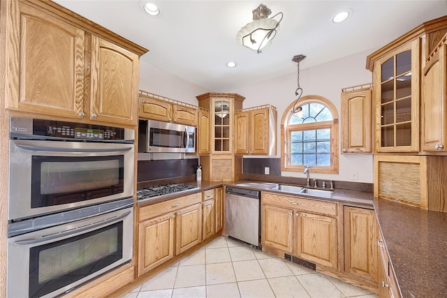 kitchen with a sink, dark countertops, stainless steel appliances, and light tile patterned flooring