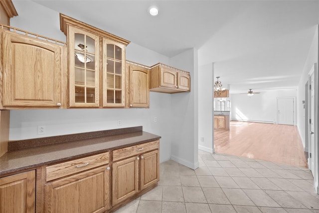 kitchen featuring a ceiling fan, dark countertops, open floor plan, glass insert cabinets, and light tile patterned flooring
