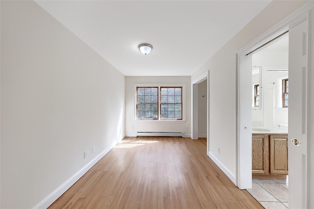empty room featuring baseboards, light wood-style flooring, and baseboard heating