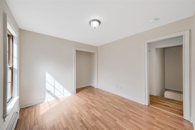 unfurnished room featuring baseboards, a baseboard radiator, and light wood-type flooring