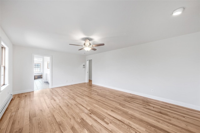 empty room featuring baseboards, a baseboard radiator, a ceiling fan, and light wood-style flooring