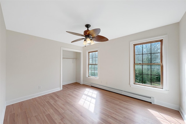 unfurnished bedroom with a ceiling fan, baseboard heating, baseboards, a closet, and light wood-style floors