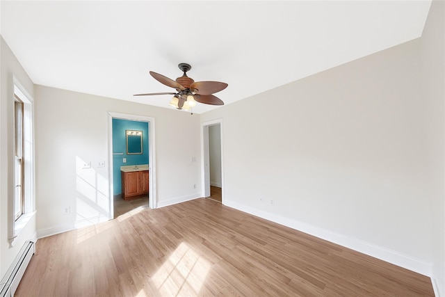 unfurnished bedroom with light wood-style floors, baseboards, ensuite bathroom, and a baseboard heating unit