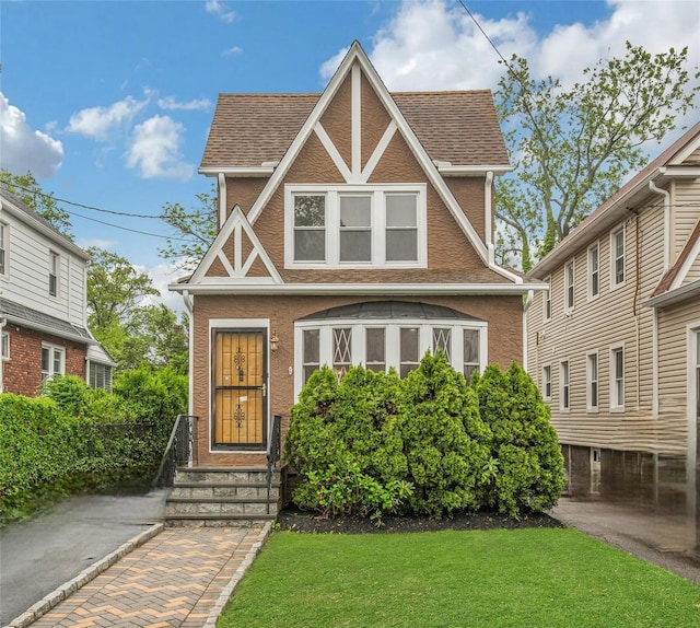 39 Crestmont Ave, Yonkers, NY 10704 - tudor home featuring a front lawn, roof with shingles, and stucco siding