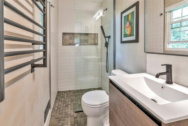 full bathroom featuring toilet, tiled shower, and vanity