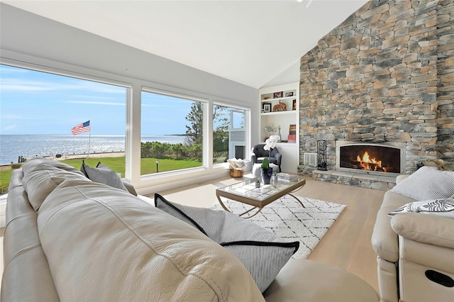 living room featuring a stone fireplace, built in features, a water view, high vaulted ceiling, and wood finished floors