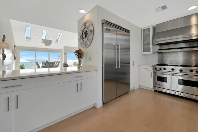 kitchen featuring light wood-style flooring, light countertops, exhaust hood, and high quality appliances