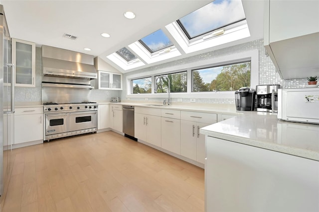 kitchen with wall chimney exhaust hood, tasteful backsplash, visible vents, and appliances with stainless steel finishes