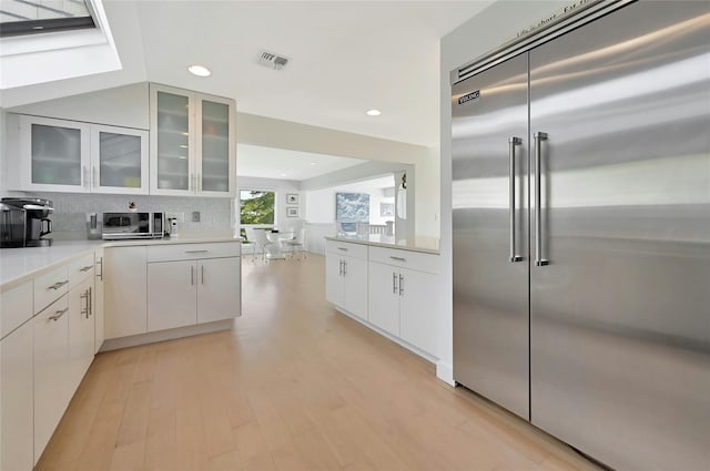 kitchen featuring recessed lighting, visible vents, white cabinetry, built in refrigerator, and light countertops
