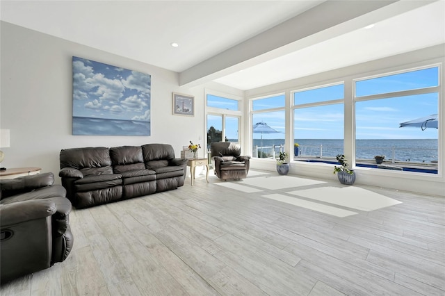 living room featuring beam ceiling, a water view, and wood finished floors