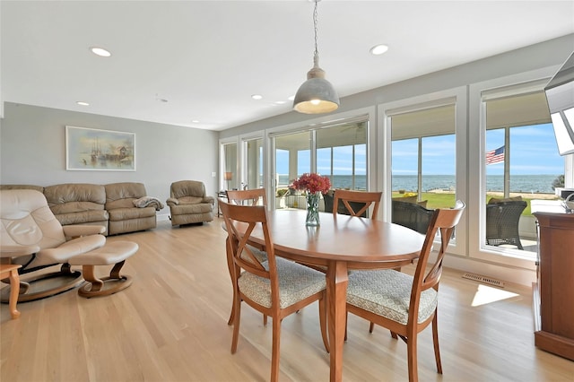 dining space featuring a water view, light wood-style floors, and recessed lighting